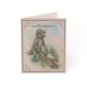 May include: A greeting card with a vintage illustration. A dinosaur-like creature wearing a flower crown pushes a wheelbarrow filled with eggs and flowers. The card reads "Warm Easter Greetings" in a decorative font, with a beige border.