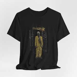 Puede incluir: Camiseta negra con un gráfico de un hombre con un traje amarillo en un bosque. El texto "what happens next is my favorite part" está sobre la figura. El diseño tiene un aspecto vintage y ligeramente desgastado.