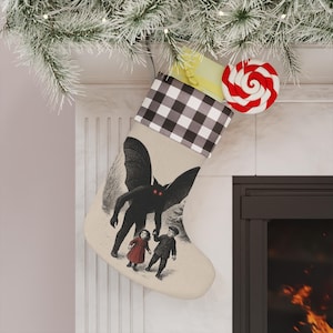 May include: A festive Christmas stocking with a black and white check cuff. The stocking displays a vintage illustration of a winged creature with red eyes and two children. A red and white swirled lollipop is attached.