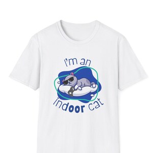 May include: White t-shirt with a blue and green graphic of a cat wearing sunglasses and holding a video game controller. The text "I'm an indoor cat" is printed below the graphic.
