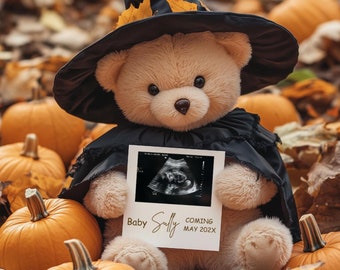 May include: A teddy bear wearing a black witch hat and a black cape holds a white card with a sonogram image and the text "Baby Sully Coming May 202x". The bear is surrounded by orange pumpkins and autumn leaves.