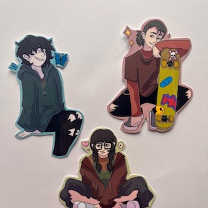 May include: Three colourful sticker cutouts of cartoon characters. One character is wearing a green hoodie and black trousers with butterfly accents. Another is leaning on a yellow skateboard. The third is wearing glasses and a brown jacket.
