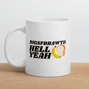 May include: White ceramic mug with a black graphic that says "DIGSFFBBAWTD HELL YEAH" with a yellow banana and a slice of bread.