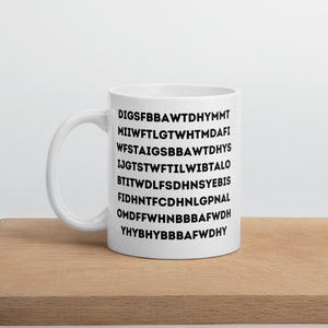 May include: White ceramic mug with a black design of a series of letters, including "DIGSFBBAWTDHYMMT", "MIIWFTLGTWHTMDAFI", "WFSTAIGSSBBAWTDHYS", "IJGTSTWFTTILWIBTALO", "BTITWDLFSDHNSYEBIS", "FIDHNTFCDHNLGPNAL", "OMDFFWHNBBBAFWDH", "YHYBHYBBBAFWDH"