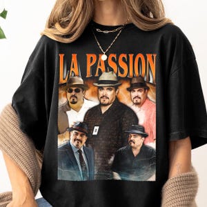 May include: Black t-shirt featuring a vintage-style graphic of five men wearing hats. The graphic reads "LA PASSION" in orange lettering.
