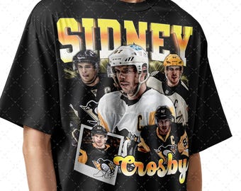 May include: Black t-shirt featuring a collage of hockey player Sidney Crosby in various poses, with the name "SIDNEY" in yellow block letters above. The name "Crosby" is in a cursive font below the images.