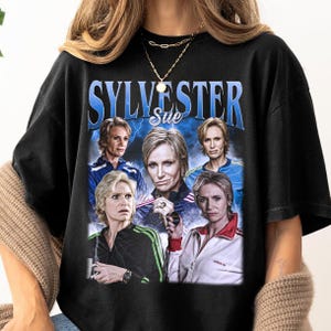 May include: Black t-shirt with a graphic print of five women with the text "Sylvester Sue" above them.