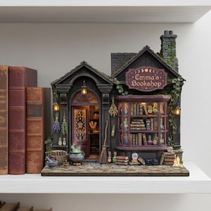 Könnte beinhalten: Ein detailliertes Miniaturmodell von "Emma's Bookshop" mit dunkler Fassade, einem lila Schild und einem Fenster mit Büchern. Der Laden verfügt über einen Schornstein, eine Tür und dekorative Elemente wie einen Besen, einen Kessel und getrocknete Kräuter. Das Modell steht auf einem weißen Regal.