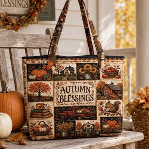 Op de afbeelding: Een gewatteerde tas met een patchworkontwerp met herfstthema's, waaronder pompoenen, een rode vrachtwagen, een schuur, een huis, zonnebloemen en een eekhoorn. Het middelste paneel bevat de tekst Autumn Blessings in een zwart lettertype.