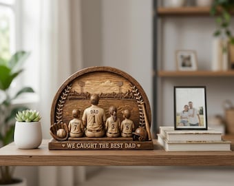 Puede incluir: Escultura de madera con temática de béisbol que representa a un padre y tres hijos, con el texto "WE CAUGHT THE BEST DAD". La escultura incluye una pelota de béisbol, un guante, un casco y un bate. La camiseta del padre está marcada con "DAD 1".