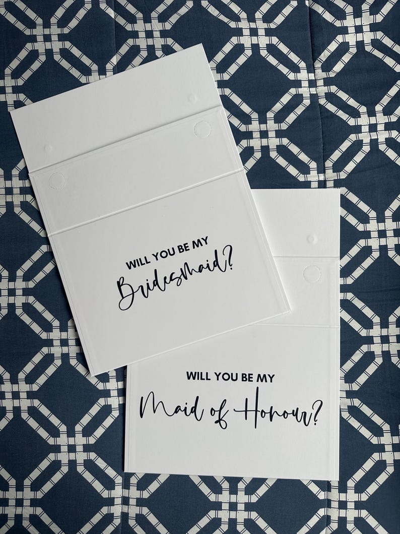 May include: Two white cards with black text. The top card says "Will you be my Bridesmaid?" and the bottom card says "Will you be my Maid of Honour?"