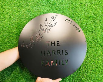 May include: Black metal sign with a leafy branch design and the text "The Harris Family Est 2009".