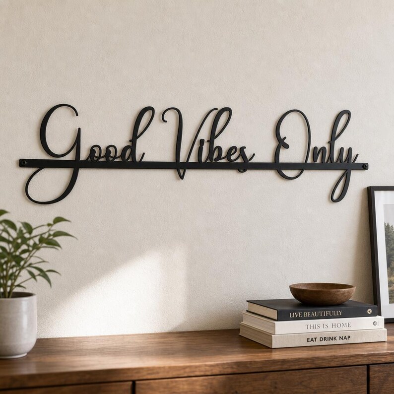May include: A black metal wall sign featuring the cursive script text Good Vibes Only. The letters are connected by a horizontal line that runs through the center of the phrase, creating a single, continuous piece of wall decor.