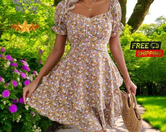 May include: A white, short-sleeved dress with a floral print in shades of yellow, pink, and blue. The dress has a square neckline and a ruffled skirt.