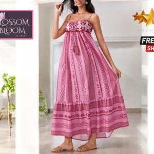 Könnte beinhalten: Ein rosafarbenes Maxikleid mit Blumenmuster und einer Schleife in der Taille. Das Kleid hat Spaghettiträger und einen Stufenrock.