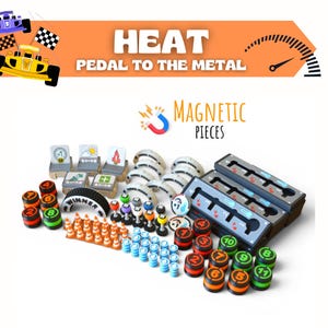 Könnte beinhalten: Ein Set aus Spielkomponenten für Heat: Pedal to the Metal, bestehend aus drei dunkelgrauen Gangschaltungskonsolen, zahlreichen nummerierten runden Spielsteinen in Orange und Grün, kleinen orangefarbenen Pylonen, blauen Zylindern und Spielkarten.