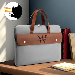 Op de afbeelding: Grijze laptoptas met een bruine leren flap en een gepersonaliseerd monogram van de letter "W" met de naam "Wilma" eronder.