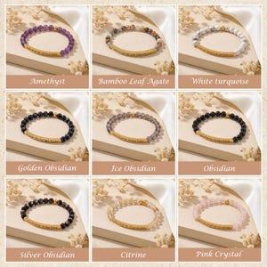 May include: Nine beaded bracelets featuring various gemstones like amethyst, obsidian, and citrine. Each bracelet has a gold-colored bar with an engraved message. The bracelets are displayed on a neutral surface with floral accents.