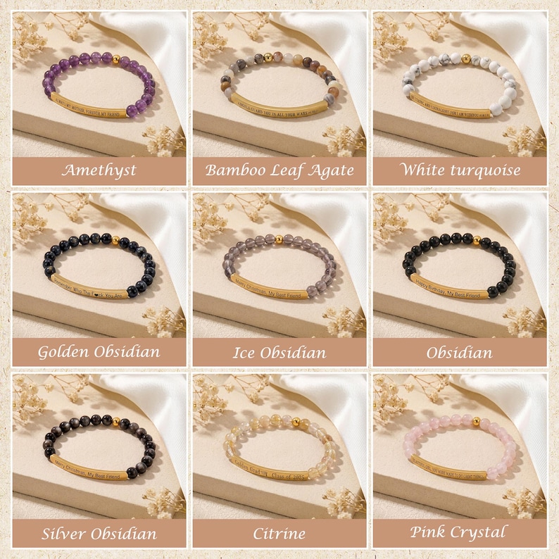 May include: Nine beaded bracelets featuring various gemstones like amethyst, obsidian, and citrine. Each bracelet has a gold-colored bar with an engraved message. The bracelets are displayed on a neutral surface with floral accents.
