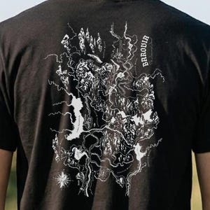 May include: A black short-sleeved t-shirt featuring a white line-art graphic on the back. The design depicts a detailed topographical map with rivers, mountains, and a compass rose, including the text "BAROVIA" printed vertically in white.