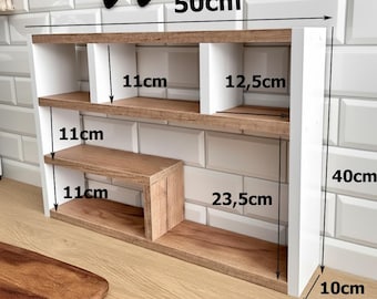 May include: A white and wood-toned wall shelf with multiple compartments. The shelf is 50cm wide, 40cm tall, and 10cm deep. It features two main shelves and a smaller, offset shelf. The shelves are 11cm deep and 12.5cm wide. The overall design is modern and functional.