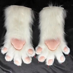 May include: A pair of white furry paw gloves with pink paw pads and pink claws. The gloves are designed to resemble animal paws, with a fluffy texture and detailed paw pads.