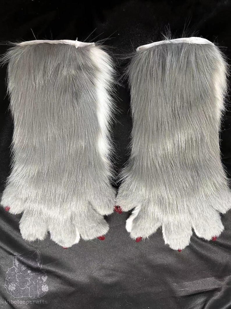 May include: A pair of grey faux fur paws with white cuffs and red painted claws. The paws have a realistic design with five toes each, and are likely part of a costume or cosplay accessory.