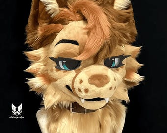 May include: A furry animal head with brown and tan fur, blue eyes, and a brown leather collar. The head is made of plush fabric and has a realistic appearance.