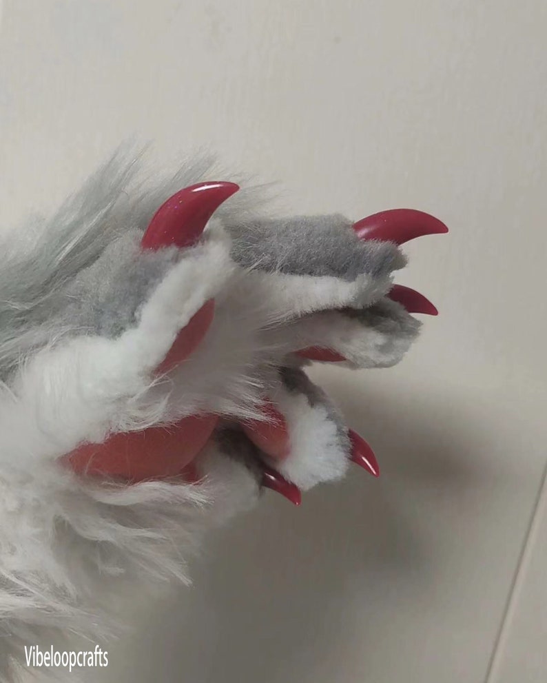 May include: A close-up of a furry paw with grey and white fur. The paw features bright red, pointed claws. The text "Vibeloopcrafts" is visible in the bottom left corner.