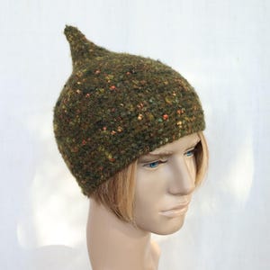 Peut inclure: Un bonnet vert tricoté avec un sommet pointu. Le chapeau est fait d'un fil texturé et moucheté dans des tons de vert, d'orange et de jaune. Le chapeau est conçu pour s'adapter parfaitement à la tête.