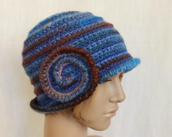 May include: A blue and brown crocheted hat with a large, spiral-shaped flower detail on the side.