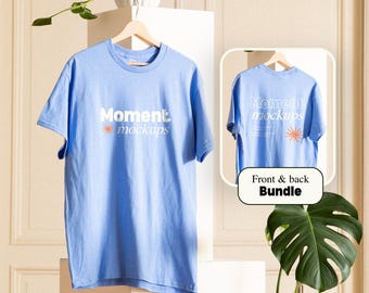 May include: A light blue t-shirt with the text "Moment mockups" printed in white on the front. The back of the shirt has the same text printed in white. The shirt is hanging on a wooden hanger.