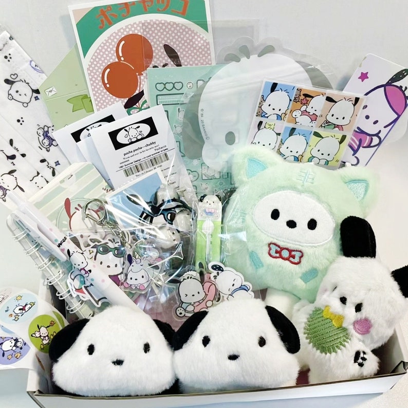 Puede incluir: Una caja de regalo llena de varios art&iacute;culos, incluyendo un juguete de peluche con una cara de gato verde y blanco, un juguete de peluche blanco y negro con una cara de gato, un llavero con un personaje de dibujos animados y una variedad de pegatinas y papeler&iacute;a. La caja est&aacute; decorada con un patr&oacute;n de lunares rosa y blanco.