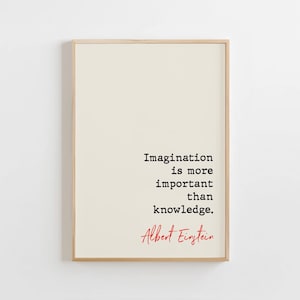 Pode incluir: Uma impressão emoldurada com fundo creme e a citação "A imaginação é mais importante que o conhecimento" em texto preto. O nome "Albert Einstein" está escrito em vermelho abaixo. A moldura é de madeira clara.