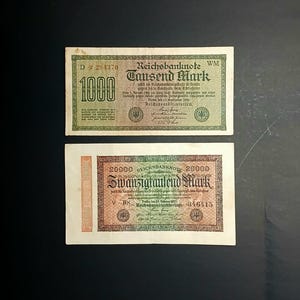 May include: Two vintage German Reichsbanknote banknotes. The top note is green and brown, with the text "Tausend Mark" and the number "1000". The bottom note is orange and green, with the text "Zwanzigtausend Mark" and the number "20000".