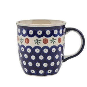 Pode incluir: Uma caneca de cerâmica azul e branca com um padrão de bolinhas e um design floral vermelho e verde ao redor da borda.