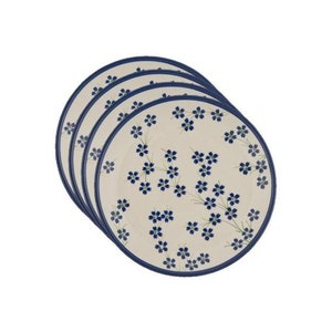 Puede incluir: Juego de cuatro platos de cena de cerámica blanca con un patrón floral azul y un borde azul oscuro.