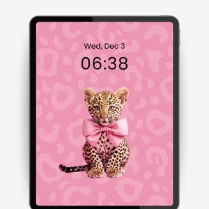 Puede incluir: Fondo de pantalla digital para iPad con un leopardo bebé con un lazo rosa sobre un fondo rosa con estampado de leopardo. La pantalla muestra la fecha y la hora. El texto en la parte superior dice "PREPPY IPAD WALLPAPER" y en la parte inferior "High Resolution • 2800 x 2800".