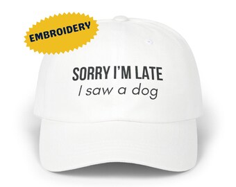 May include: White baseball cap with black embroidered text that reads "SORRY I'M LATE / I saw a dog".