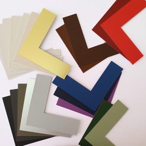 May include: Assortment of 10 different colored mat boards in the shape of an L. The colors are gold, brown, red, blue, navy, purple, green, gray, black, and beige.