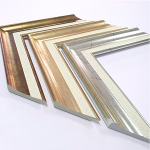 May include: Three picture frames with ornate, decorative edges. The frames are made of wood and have a white, gold, and silver finish. The frames are arranged in a staggered pattern, with the largest frame at the bottom and the smallest frame at the top.