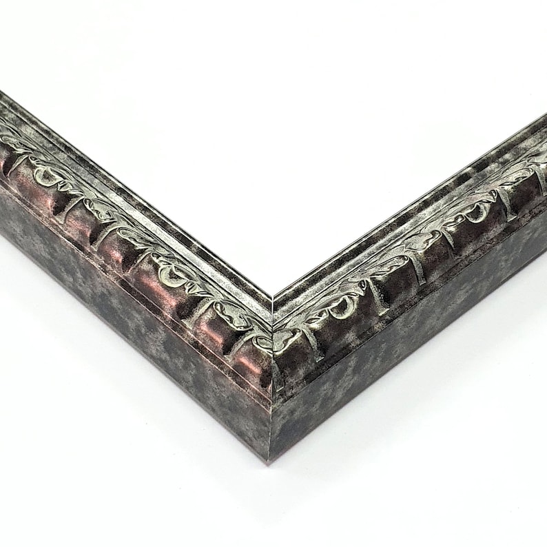 May include: Close-up of a corner of a silver and black ornate picture frame. The frame has a raised, textured design.