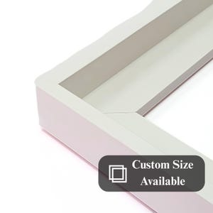 Pode incluir: Close-up de um canto de moldura branca com interior cinza claro. A moldura tem um design limpo e moderno. O texto na imagem diz "Custom Size Available".