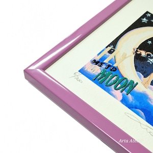 Puede incluir: Una impresión enmarcada con una ilustración colorida de una mujer volando a la luna. La impresión está firmada y numerada 6/200. El marco es de color morado claro.