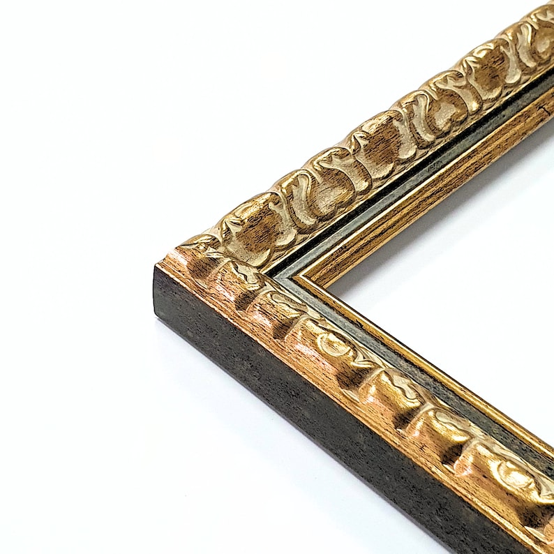 May include: Close-up of a decorative picture frame corner. The frame features a dark brown base with ornate gold-colored detailing. The design includes carved floral patterns and a contrasting inner border.