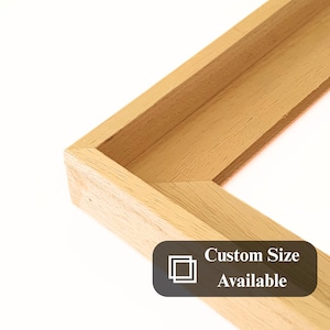 Peut inclure: Gros plan sur un coin de cadre en bois clair avec des veines visibles. Le texte "Custom Size Available" est affiché sur une étiquette rectangulaire gris foncé dans le coin inférieur droit.