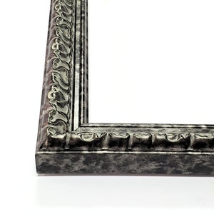 May include: A silver picture frame with an ornate design. The frame has a distressed finish and a raised edge.