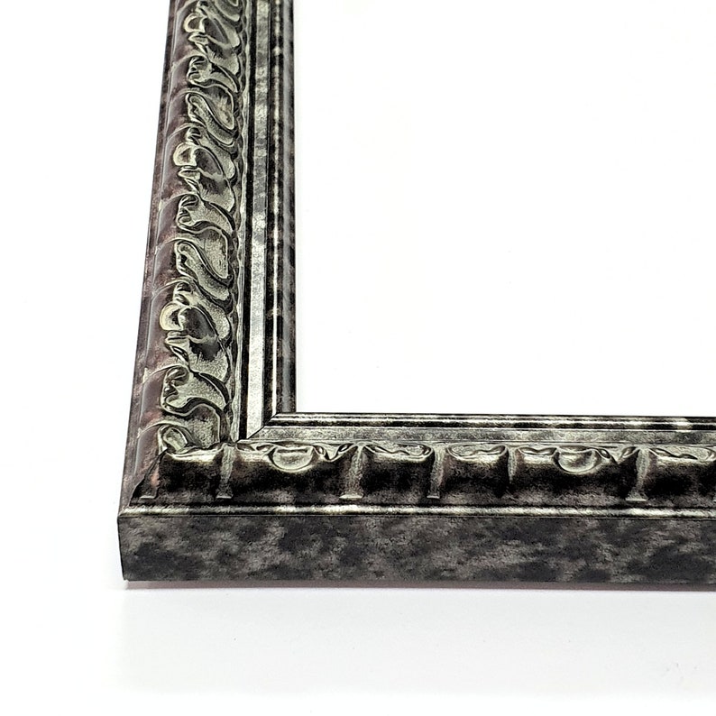 May include: A silver picture frame with an ornate design. The frame has a distressed finish and a raised edge.
