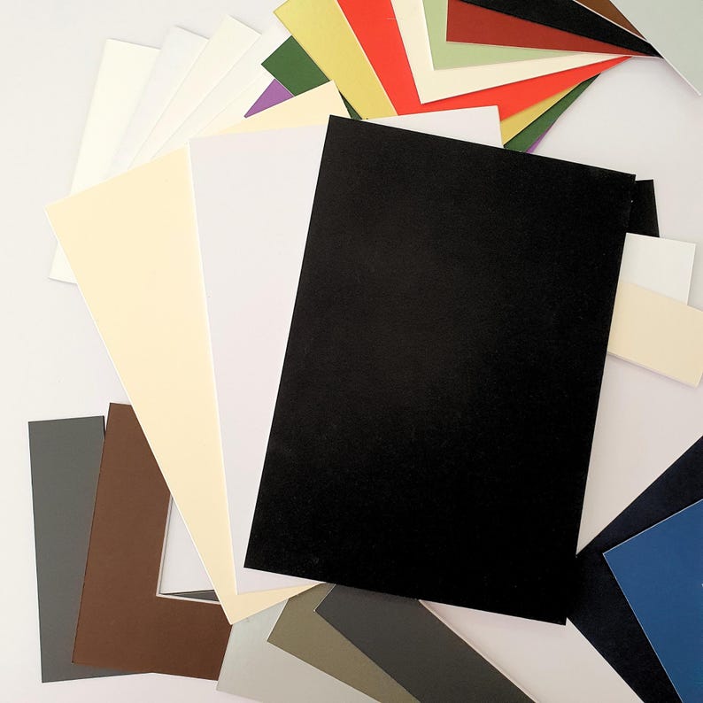 May include: A variety of colored cardstock paper sheets in different sizes. The sheets are arranged in a fan shape, with the black sheet at the top.