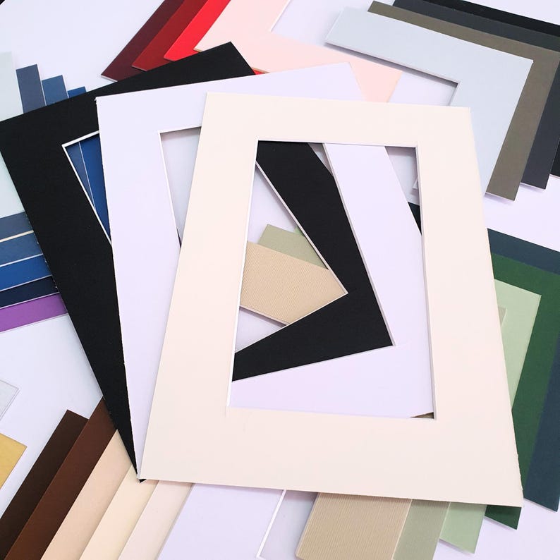 May include: A variety of colored cardstock mats for framing photos or artwork. The mats are in different sizes and colors, including black, white, red, pink, green, blue, and brown.